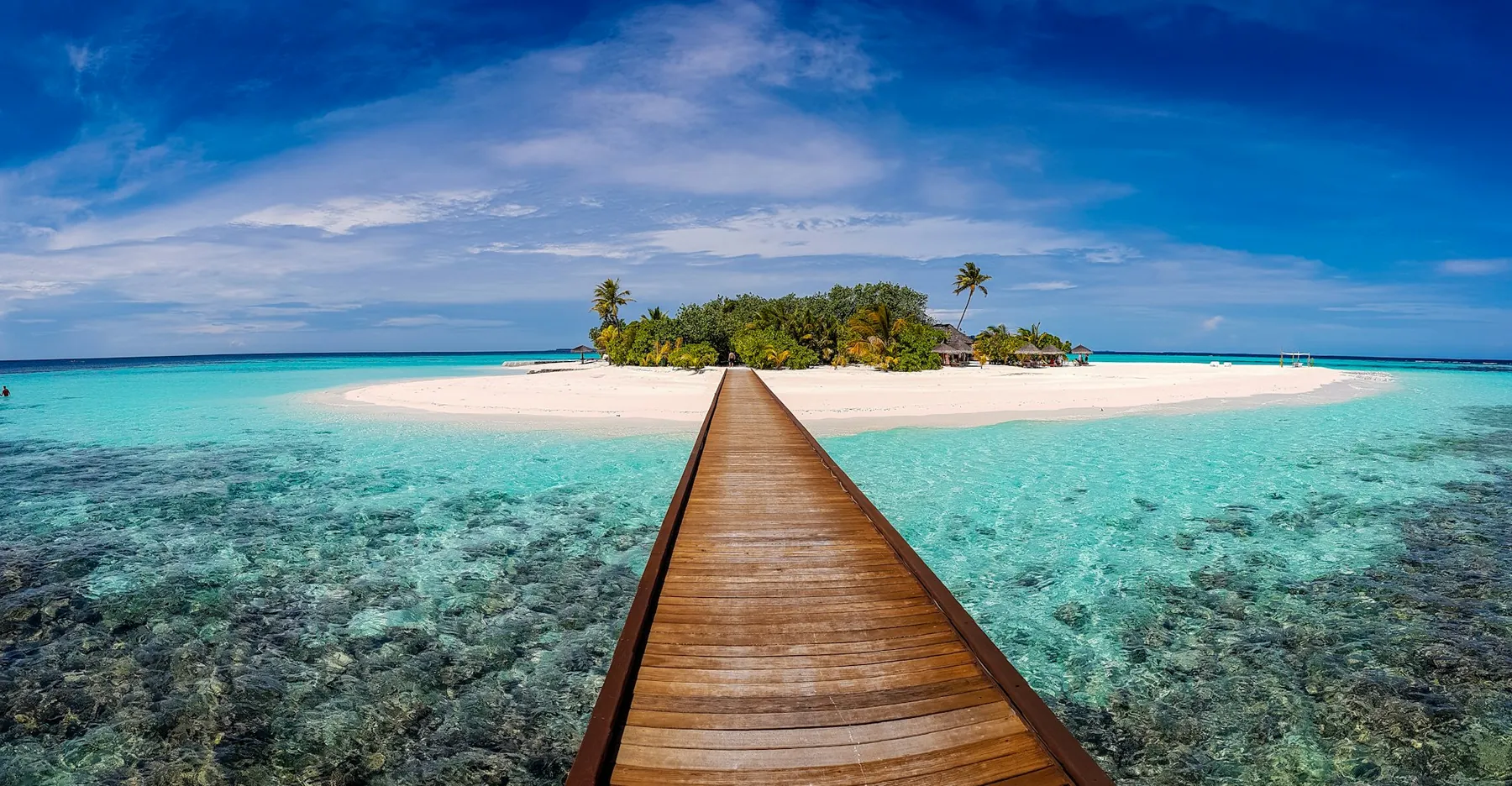 Muelle de madera hacia una isla de arena blanca